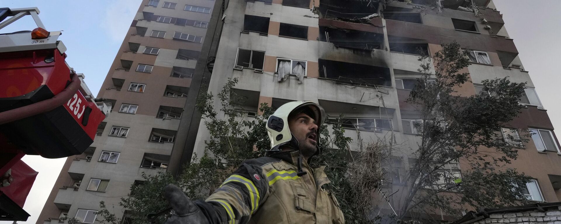 ينادي رجل إطفاء زملاءه في موقع انفجار في مجمع سكني في شمال طهران، إيران، الجمعة 13 يونيو 2025. - سبوتنيك عربي, 1920, 13.06.2025