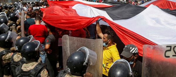 قوات الأمن العراقية تقف أمام متظاهرين في احتجاجات مناهضة للحكومة أثناء زيارة رئيس الوزراء العراقي مصطفى الكاظمي إلى البصرة، العراق، 15 يوليو 2020. - سبوتنيك عربي