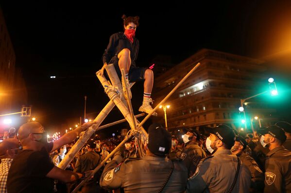 أشخاص يتظاهرون ضد رئيس الوزراء الإسرائيلي بنيامين نتنياهو احتجاجا على قضايا الفساد المتورط فيها وسوء الوضع الاقتصادي الناجم عن الإغلاق خلال أزمة فيروس كورونا (كوفيد-19)، بالقرب من منزله في القدس، 22 أغسطس 2020 - سبوتنيك عربي