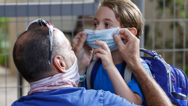 أب يضع كمامة طبية لابنه قبل دخول المدرسة في اليوم الأول من العام الدراسي في مدينة تل-أبيب، إسرائيل 1 سبتمبر 2020 - سبوتنيك عربي