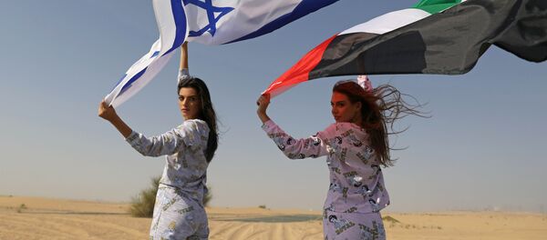 عارضة الأزياء الإسرائيلية ماي تاغر، تحمل العلم الإسرائيلي، تقف مع عارضة الأزياء الروسية المقيمة في دبي أناستاسيا، وتحمل العلم الإماراتي، خلال جلسة تصوير لمجموعة البيجاما للعلامة التجارية الإسرائيلية FIX's Princess Collection في دبي، الإمارات العربية المتحدة  8 سبتمبر  2020. - سبوتنيك عربي