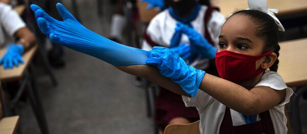 تلميذة ترتدي كمامة وقفازات كإجراء احترازي وسط انتشار فيروس كورونا خلال الفصل الدراسي في هافانا، كوبا، 2 نوفمبر 2020 - سبوتنيك عربي