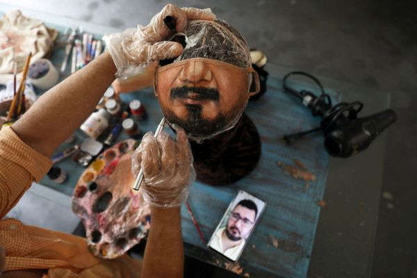 الفنان التشكيلي البرازيلي، خورخي سيلفا روريز، يرسم قناعًا وقائيًا بناءا على طلب الزيون، حيث ينظر إلى صورة الرجل على هاتفه الخلوي، ويعمل في منزله في ريو دي جانيرو، وسط تفشي مرض فيروس كورونا (كوفيد-19) في البرازيل، 10 نوفمبر 2020. - سبوتنيك عربي