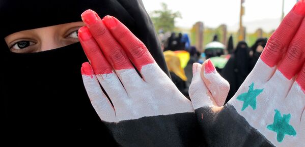 امرأة تظهر كفة يدها المرسوم عليها ألوان العلمين اليمني والسوري خلال مظاهرة حاشدة ضد حكم الرئيس علي عبد الله صالح في العاصمة اليمنية صنعاء، 4 نوفمبر 2011 - سبوتنيك عربي