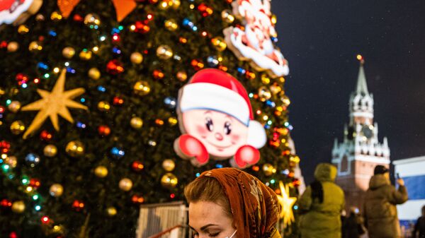 امرأة ترتدي كمامة وهي تسير بجوار شجرة عيد الميلاد في الساحة الحمراء وسط موسكو، 1 ديسمبر 2020 - سبوتنيك عربي