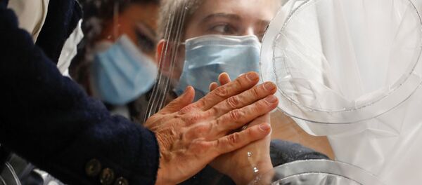 طفل في المستشفى يلامس يد والده من خلال حاجز بلاستيكي لمنع تعرضه لخطر التلوث أو انتقال مرض (كوفيد-19) في قسم إعادة تأهيل الأطفال وإعاقات النمو في مستشفى سان رافاييل، وذلك في إطار تلبية  رغبة الأطفال في رؤية أقاربهم وعناقهم في عيد الميلاد المجيد في روما، إيطاليا، 22 ديسمبر 2020. - سبوتنيك عربي