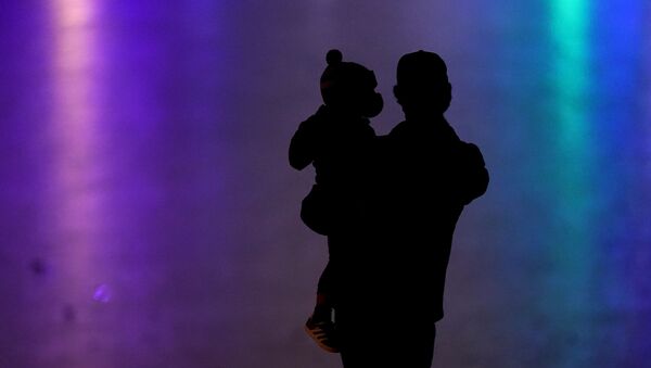 رجل يحمل طفل ويرتديان كمامات واقية من فيروس كورونا المستجد 26 ديسمبر 2020  كانساس  - سبوتنيك عربي