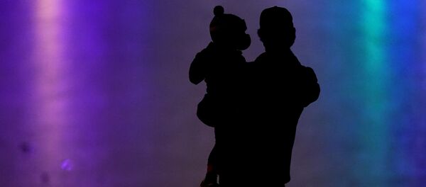 رجل يحمل طفل ويرتديان كمامات واقية من فيروس كورونا المستجد 26 ديسمبر 2020  كانساس  - سبوتنيك عربي