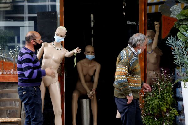 بلوتارخوس بلوتارشو، إلى اليسار، يحمل عارضة أزياء ترتدي كمامة في متجره وسط نيقوسيا، قبرص، 11 يناير 2021 - سبوتنيك عربي