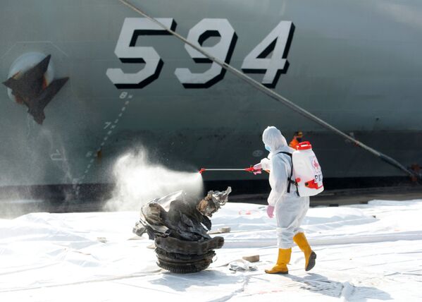 عضو في الصليب الأحمر الإندونيسي يقوم بتعقيم قطعة من الحطام تم استردادها من البحر، يعتقد أنها من توربين رحلة طيران سريويجايا SJ182 التي تحطمت في البحر، في جاكرتا، إندونيسيا، 11 يناير 2021 - سبوتنيك عربي