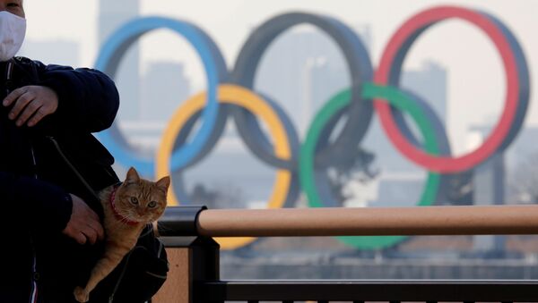 رجل يحمل قطة في حقيبته يقف على خلفية الحلقات الأولمبية العملاقة وسط تفشي مرض فيروس كورونا (كوفيد-19) في طوكيو، اليابان، 22 يناير 2021 - سبوتنيك عربي