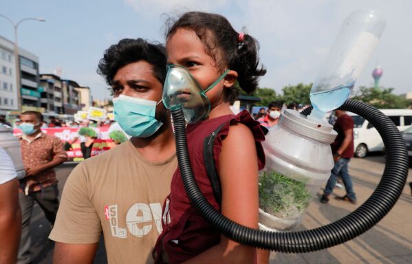 فتاة صغيرة ترتدي قناع الأكسجين لإثبات إمكانية ضخ الأكسجين من شجرة في زجاجة في المستقبل، خلال احتجاج ضد ممارسات الحكومة لإزالة الغابات في غابات الحياة البرية الرئيسية في سريلانكا من أجل التطورات الحديثة في كولومبو، سريلانكا، 22 مارس 2021 - سبوتنيك عربي