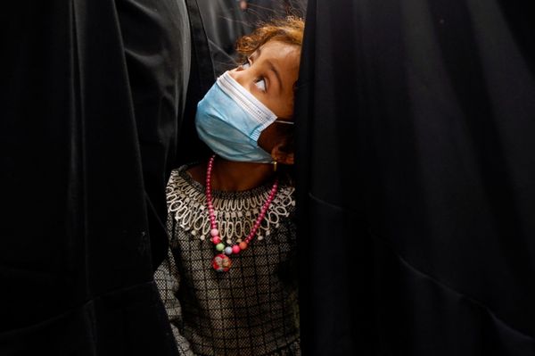 طفلة ترتدي كمامة واقية تف برفقة والدتها لاستلام نصيبهما من الطعام من جمعية خيرية في النجف قبل بدء شهر رمضان، العراق 12 أبريل 2021 - سبوتنيك عربي