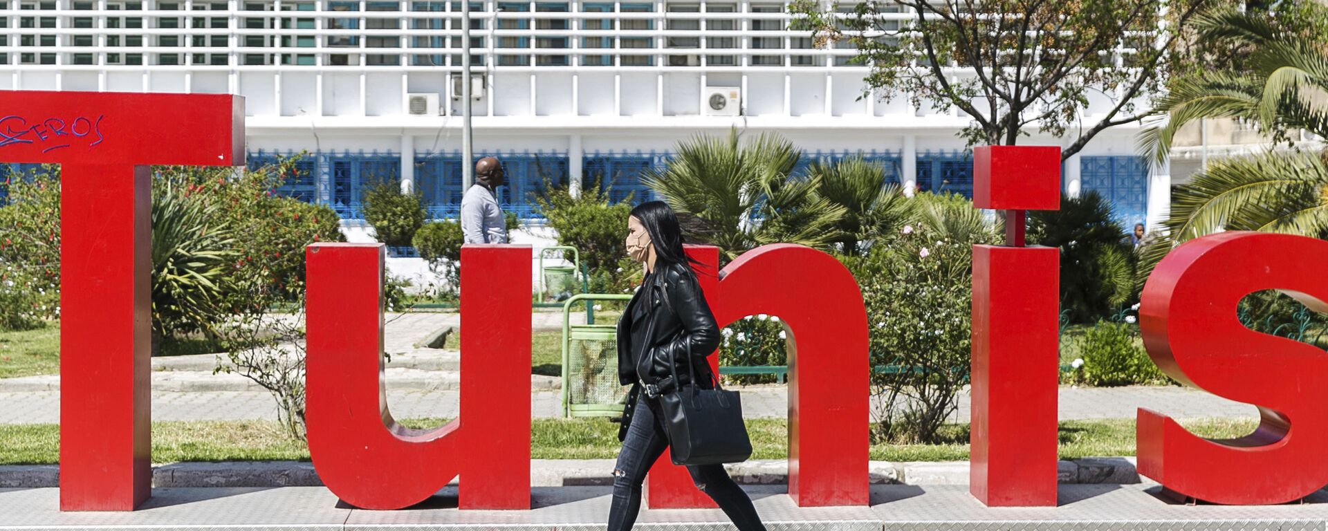 امرأة تسير على خلفية شعار تونس في مدينة  تونس، 9 أبريل 2021 - سبوتنيك عربي, 1920, 05.10.2022