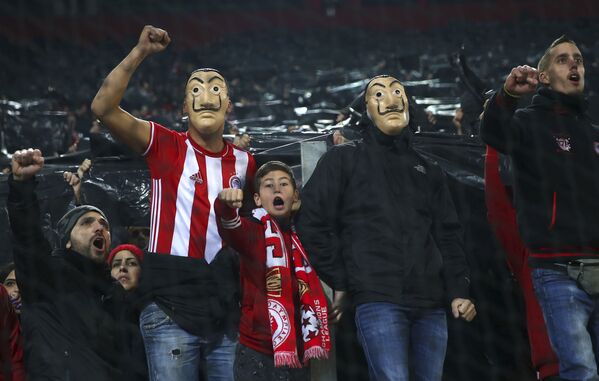 مشجعون يونانيون يرتدون أقنعة على شكل وجه سلفادور دالي، المستوحاة من المسلسل الإسباني الشهير لا كاسا دي بابيل ( بيت من ورق وبيت المال)، أثناء مباراة مجموعة اف من بطولة دوري أبطال أوروبا، بين فريقي أي سي ميلان وأوليمبيكوس في ملعب جيورجيوس كارايسكاكيس في بيراوس بالقرب من أثينا، اليونان 13 ديسمبر 2018 مشجعون يونانيون يرتدون أقنعة على شكل وجه سلفادور دالي، المستوحاة من المسلسل الإسباني الشهير لا كاسا دي بابيل ( بيت من ورق وبيت المال)، أثناء مباراة مجموعة اف من بطولة دوري أبطال أوروبا، بين فريقي أي سي ميلان وأوليمبيكوس في ملعب جيورجيوس كارايسكاكيس في بيراوس بالقرب من أثينا، اليونان 13 ديسمبر 2018 - سبوتنيك عربي