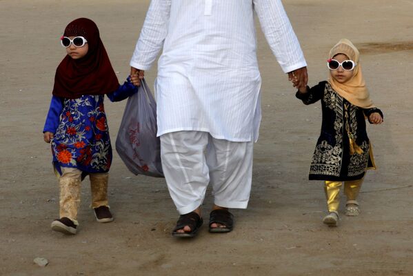 أب مع طفليه بعد صلاة عيد الفطر في مدينة كاراتشي، باكستان 13 مايو 2021 - سبوتنيك عربي