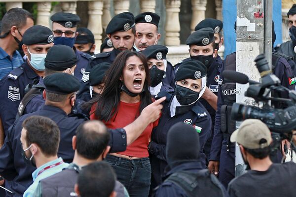 عناصر الشرطة يوقفون متظاهرة خلال مظاهرة تضامنية مع الشعب الفلسطيني بالقرب من السفارة الإسرائيلية في العاصمة الأردنية عمان، الأردن 9 مايو 2021 - سبوتنيك عربي