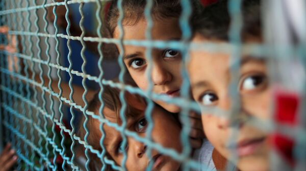 أطفال ينظرون من نافذة مدرسة الأنروا. يذكر أنه نزح ما يقرب 34 ألف من أهالي قطاع غزة إلى مدراس الأونروا بعد قصف الطيران الحربي الإسرائيلي منازلهم، فلسطين بتاريخ 18 مايو 2021 - سبوتنيك عربي