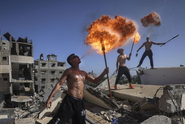 أعضاء فريق بار وولف الفلسطيني من غزة يؤدون عرضًا ناريًا على أنقاض مبنى دمرته الغارات الجوية الإسرائيلية، 26 مايو 2021 - سبوتنيك عربي