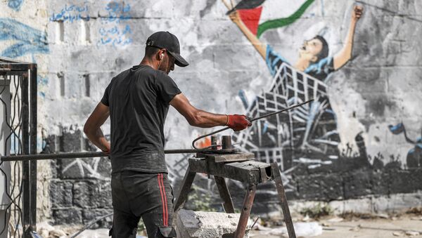 عامل يقوم بإعادة تدوير المواد اللازمة لإعادة الإعمار والبناء من ركام المباني في مدينة غزة، بعد تبادل إطلاق النار بين قطاع غزة وإسرائيل في مايو الماضي، 5 يونيو 2021 - سبوتنيك عربي