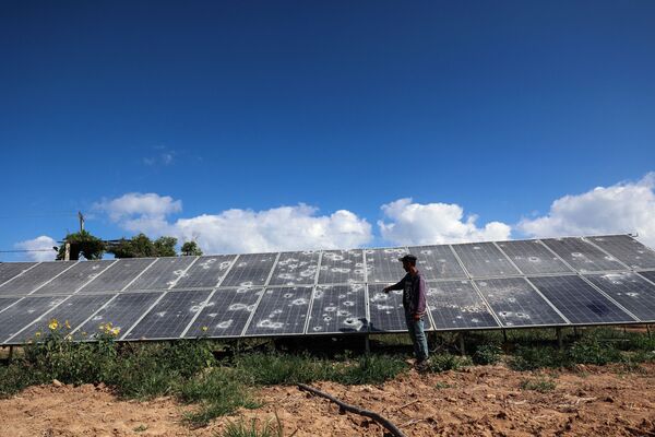 مزارع فلسطيني يعرض الألواح الشمسية التالفة في حقل في بيت لاهيا شمال قطاع غزة بالقرب من الحدود الإسرائيلية، في 18 يونيو 2021، والتي تعرضت لغارات جوية إسرائيلية خلال التصعيد العسكري بيت الجانبين في مايو/ أيار الماضي. - سبوتنيك عربي
