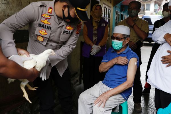 رئيس شرطة المنطقة، غاليه أبريا، يمنح دجاجة حية لجيجي جاينودين، البالغ من العمر 68 عامًا، من قرية سينداغلايا، الذي تلقى للتو جرعته الأولى من لقاح كوفيد-19، مقاطعة جاوة الغربية، إندونيسيا، 15 يونيو 2021. - سبوتنيك عربي