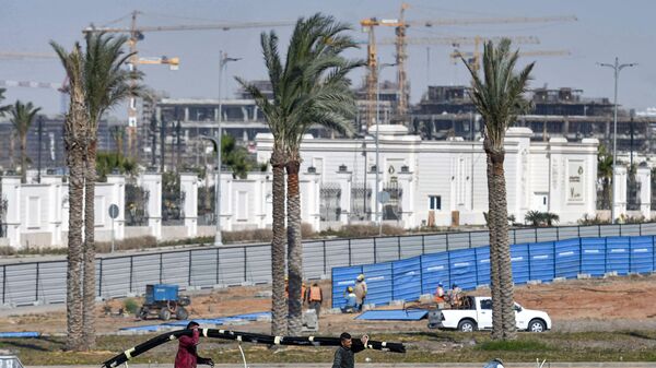 عمال بناء يسيرون على خلفية أعمال بناء في العاصمة الإدارية الجديدة، مصر 7 مارس 2021 - سبوتنيك عربي