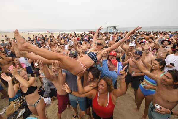 الجمهور يرفع البطلة آني سيرايت-نيوتن في الهواء بعد فوزها في مسابقة هيرموسا بيتش السنوية بنسختها الـ47، حيث يجب على المشاركين الجري لمسافة ميل واحد، والتجديف على لوح التزلج على الأمواج لمسافة ميل واحد، وشرب ستة عبوات من البيرة في شاطئ هيرموسا، كاليفورنيا  4 يوليو 2021 - سبوتنيك عربي