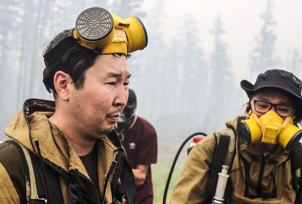 متطوعون من جمعية خيرية يساعدون في اخماد الحرائق بالقرب من قرية ماغاراس في ياقوتيا، روسيا 15 يوليو 2021 - سبوتنيك عربي