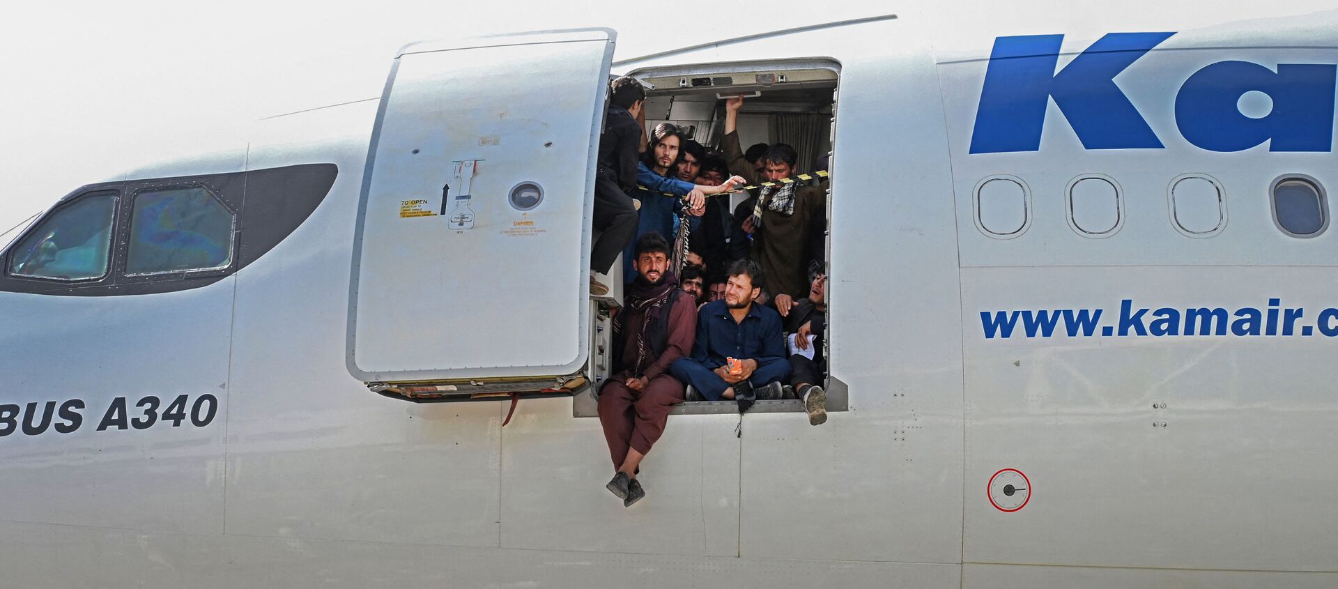 أفغان يجلسون على باب طائرة في مطار كابول - سبوتنيك عربي, 1920, 25.08.2021