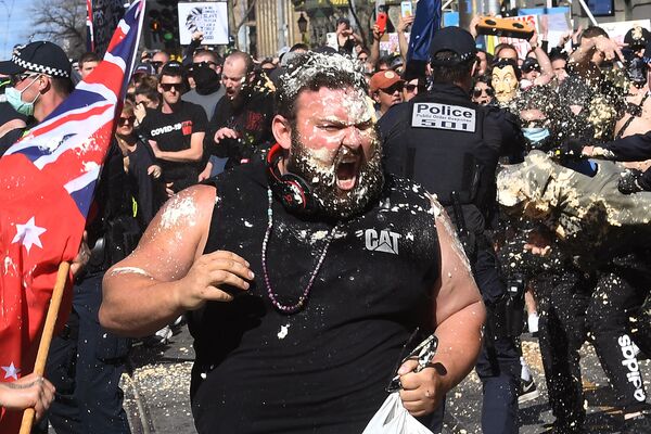 يتفاعل أحد المتظاهرين مع رذاذ الفلفل الذي استخدمته الشرطة خلال مسيرة مناهضة للإغلاق السادس لاحتواء نتفشي كورونا في ملبورن، أستراليا 21 أغسطس 2021 - سبوتنيك عربي