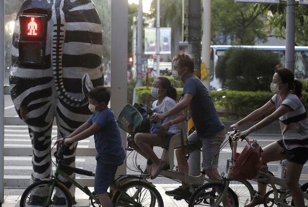 راكبو الدراجات يرتدون كمامات، ينتظرون عند إشارة مرور على شكل حمار وحشي في تايبيه، تايوان 6 أكتوبر 2021 - سبوتنيك عربي