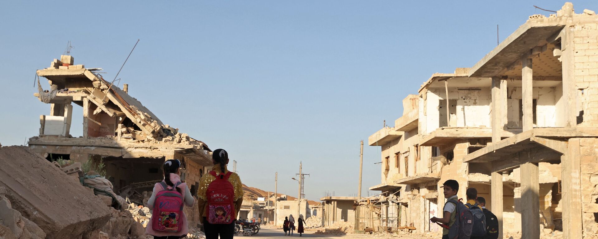 أطفال يمشون بين الأنقاض أثناء حضورهم اليوم الأول من المدرسة في قرية في ريف إدلب شمال غرب سوريا، 9 أكتوبر 2021. - سبوتنيك عربي, 1920, 28.08.2022