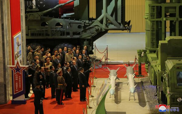 زعيم كوريا الشمالية كيم جونغ أون يتحدث إلى المسؤولين بجوار الأسلحة والمركبات العسكرية المعروضة، بما في ذلك الصواريخ الباليستية العابرة للقارات (ICBM)، في معرض تطوير الدفاع، في بيونغ يانغ، كوريا الشمالية، 12 أكتوبر 2021 . - سبوتنيك عربي