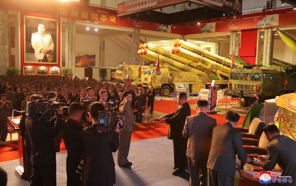 زعيم كوريا الشمالية كيم جونغ أون يتحدث إلى المسؤولين بجوار الأسلحة والمركبات العسكرية المعروضة، بما في ذلك الصواريخ الباليستية العابرة للقارات (ICBM)، في معرض تطوير الدفاع، في بيونغ يانغ، كوريا الشمالية، 12 أكتوبر 2021 . - سبوتنيك عربي