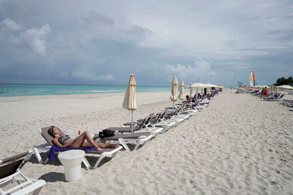 سائحة توجه نفسها تجاه الشمس وسط مخاوف من انتشار فيروس كورونا (كوفيد-19) في فاراديرو، كوبا، 22 أكتوبر 2021 - سبوتنيك عربي