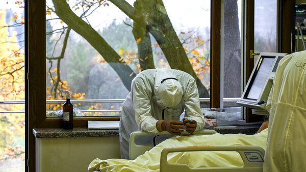 أحد أعضاء الطاقم الطبي يستريح بجانب مريض مصاب بفيروس كوفيد-19 في وحدة العناية المركزة في مستشفى لوزينيتس في صوفيا، بلغاريا 9 نوفمبر 2021. - سبوتنيك عربي