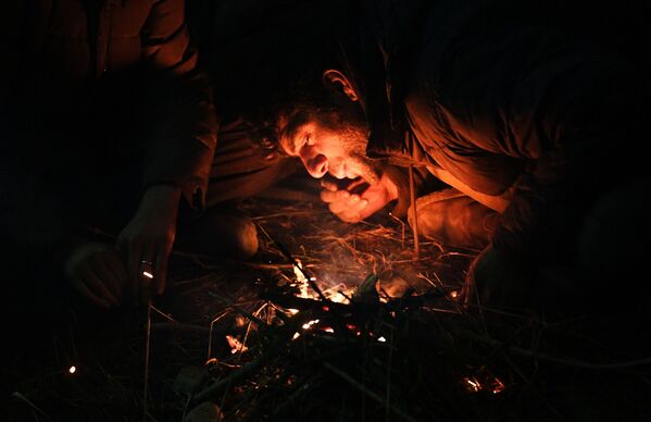 لاجئ من الشرق الأوسط يشعل ناراً بالقرب من نقطة تفتيش في بروزجي على الحدود البيلاروسية البولندية. في 8 نوفمبر 2021 - سبوتنيك عربي