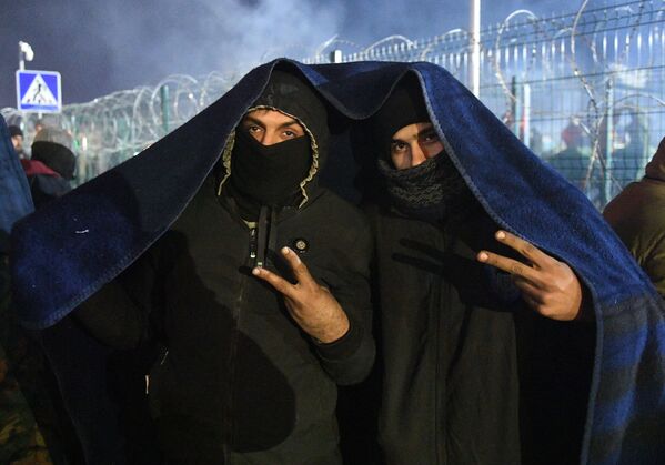 لاجئان من الشرق الأوسط يقفان للتصوير أما الصحافيين في نقطة تفتيش في بروزجي على الحدود البيلاروسية البولندية، 15 نوفمبر 2021 - سبوتنيك عربي