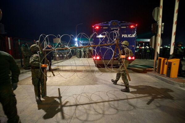 الشرطة البولندية تضع حاجزاً من الأسلاك الشائكة بالقرب من نقطة تفتيش في بروزجي على الحدود البيلاروسية البولندية، 15 نوفمبر 2021 - سبوتنيك عربي