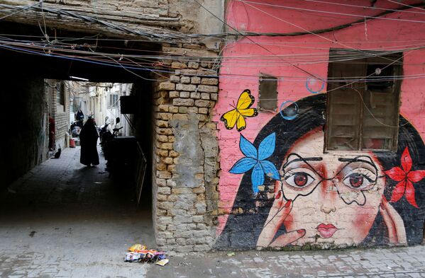 صورة تظهر لوحة جدارية رسمتها مجموعة من الرسامين العراقيين الذين تطوعوا لطلاء جدران منازل الأحياء القديمة لتزيين مدينتهم في حي الكاظمية في بغداد، العراق، 30 نوفمبر 2021 - سبوتنيك عربي