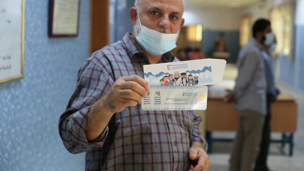 رجل يُظهر بطاقته الانتخابية داخل مركز اقتراع في طرابلس، ليبيا في 8 نوفمبر 2021 - سبوتنيك عربي