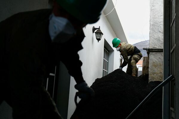 عسكري إسباني ينظف رماد بركان كومبر فيجا خارج منزل في حي لاس مانشاس، في جزيرة لا بالما الكناري، إسبانيا، 16 ديسمبر 2021 - سبوتنيك عربي