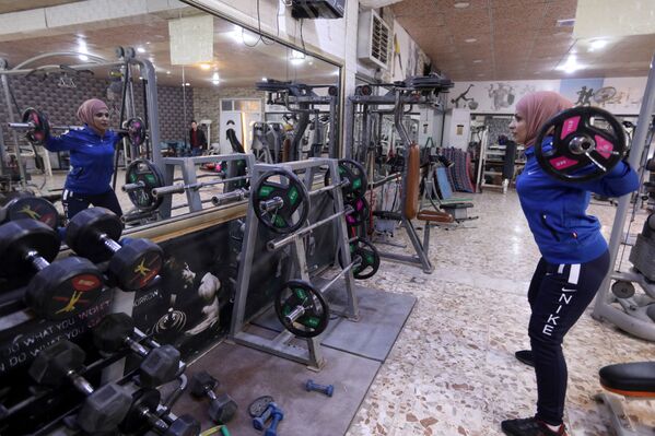 الملاكمة العراقية، بشرى عبد الزهرة، البالغة من العمر 36 عامًا، تتدرب بالأوزان في صالة ألعاب رياضية في النجف، العراق ، 24 ديسمبر 2021 - سبوتنيك عربي