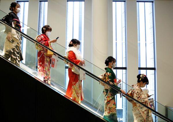 نساء يرتدين الكيمونو يركبن سلمًا متحركًا في مكان الاحتفال بيوم بلوغ سن الرشد في طوكيو، اليابان، 10 يناير 2022. - سبوتنيك عربي