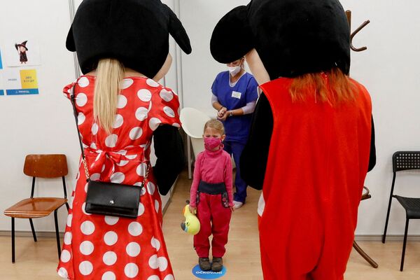 طاقم طبي يرتدي أزياء يقف أمام طفل تلقى حقنة ضد فيروس كورونا في مركز تطعيم شامل في براغ، جمهورية التشيك، 8 يناير 2022. - سبوتنيك عربي