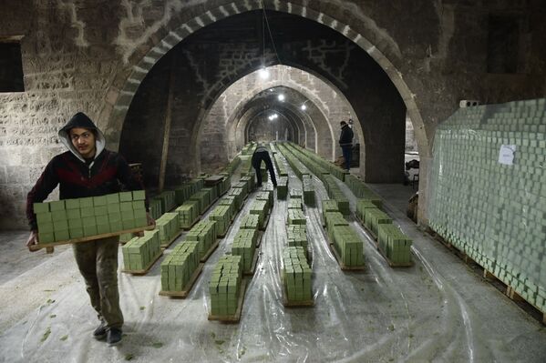 عامل سوري يحمل مجموعة من صابون الغار في مصنع الجبيلي للصابون، الواقع في مدينة حلب القديمة شمال سوريا، 24 يناير 2022. - سبوتنيك عربي