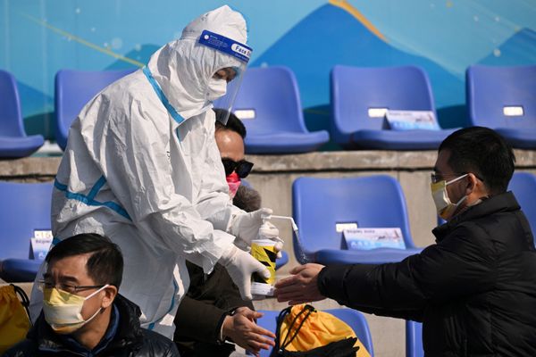 موظف يرتدي زي الحماية الشخصية يرش المطهر على يدي المتفرج في نهاية نهائي التزلج الحر للرجال خلال دورة الألعاب الأولمبية الشتوية في بكين 2022 في بيغ آير شوغانغ، 9 فبراير 2022. - سبوتنيك عربي