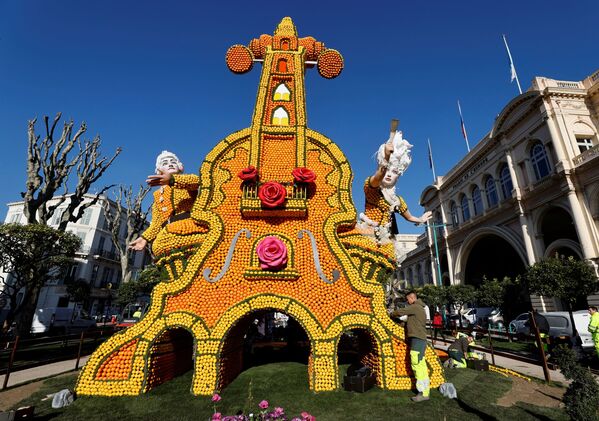 عامل يضع اللمسات الأخيرة على تمثال مصنوع من الليمون والبرتقال يُدعى "أيدا"، خلال مهرجان الليمون الـ 88 بعنوان "الأوبرا والرقص" في مينتون، فرنسا، 10 فبراير 2022. - سبوتنيك عربي