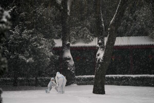 عمال يرتدون بدلات واقية يصنعون تميمة الأولمبياد تميمة من الثلج في الخارج في دورة الألعاب الأولمبية الشتوية 2022  في بكين، الصين 13 فبراير 2022. - سبوتنيك عربي